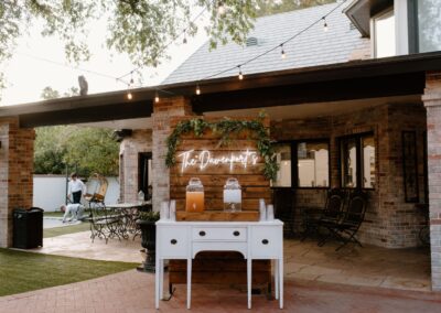 white buffet table with drink dispensers in front of a wood pallet wall backdrop