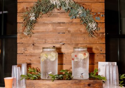 white buffet table with drink dispensers in front of a wood pallet wall backdrop