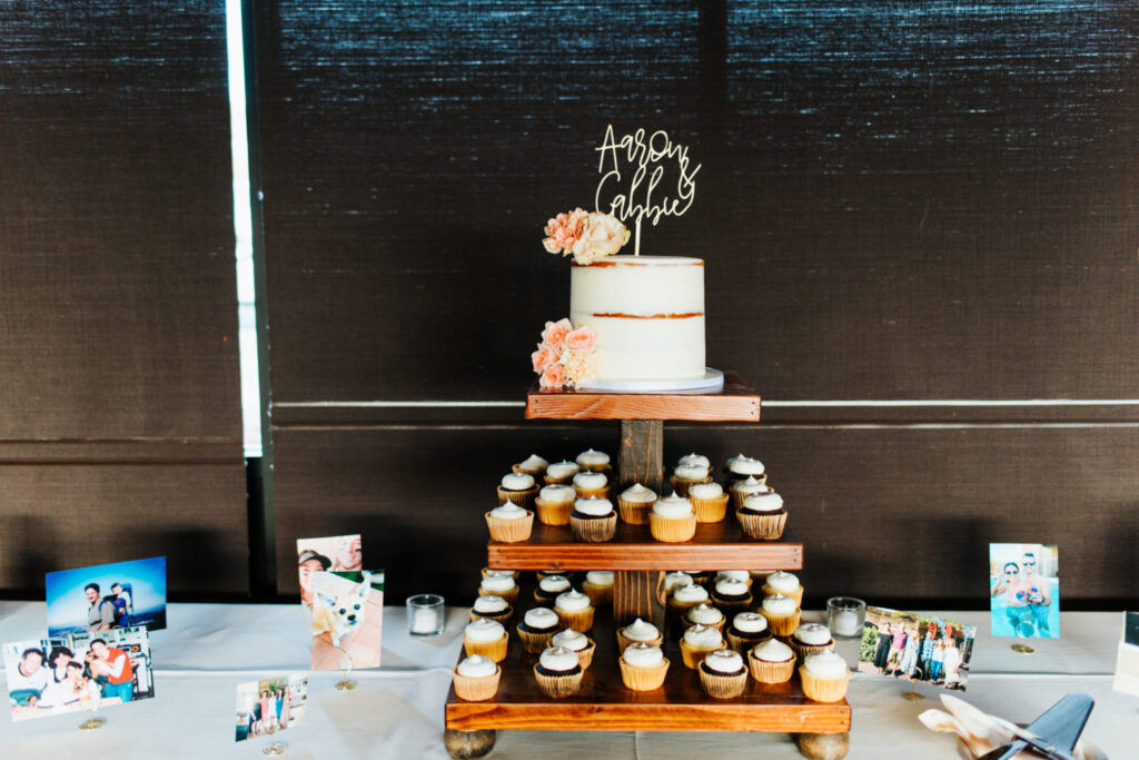 three tiered wood stand with cupcakes and a wedding cake on top