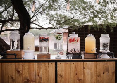 Seven miscellaneous drink dispensers sitting on a wood bar