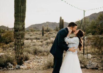 bride and groom kissing while dancing on wood dance floor desert wedding venue