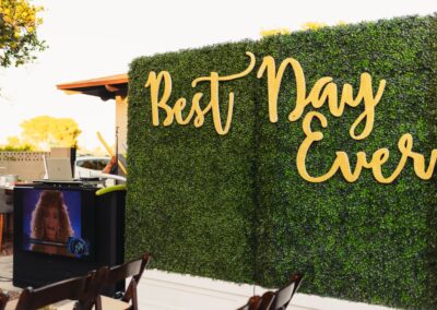 boxwood greenery hedge with "Best day every" sign photo backdrop