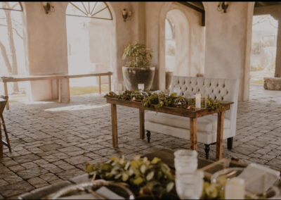 sweetheart table with greenery on it and a square backed loveseat placed behind it