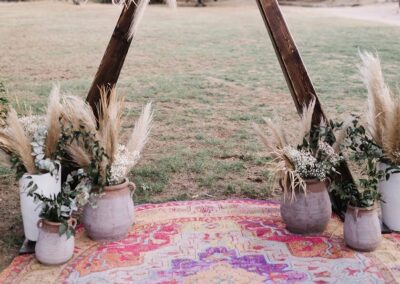 terracotta pots and white ceramic vases in front of triangle wedding arch