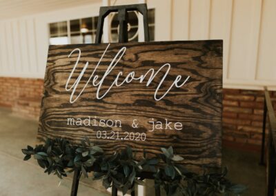 wood welcome sign on an easel with greenery