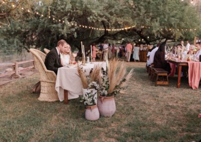 bride and groom sitting at sweetheart table with terracotta pots and foliage around