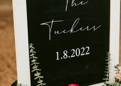 white framed chalkboard with greenery and pink and red flowers