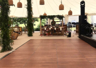 dark wood dance floor set up under a wedding tent