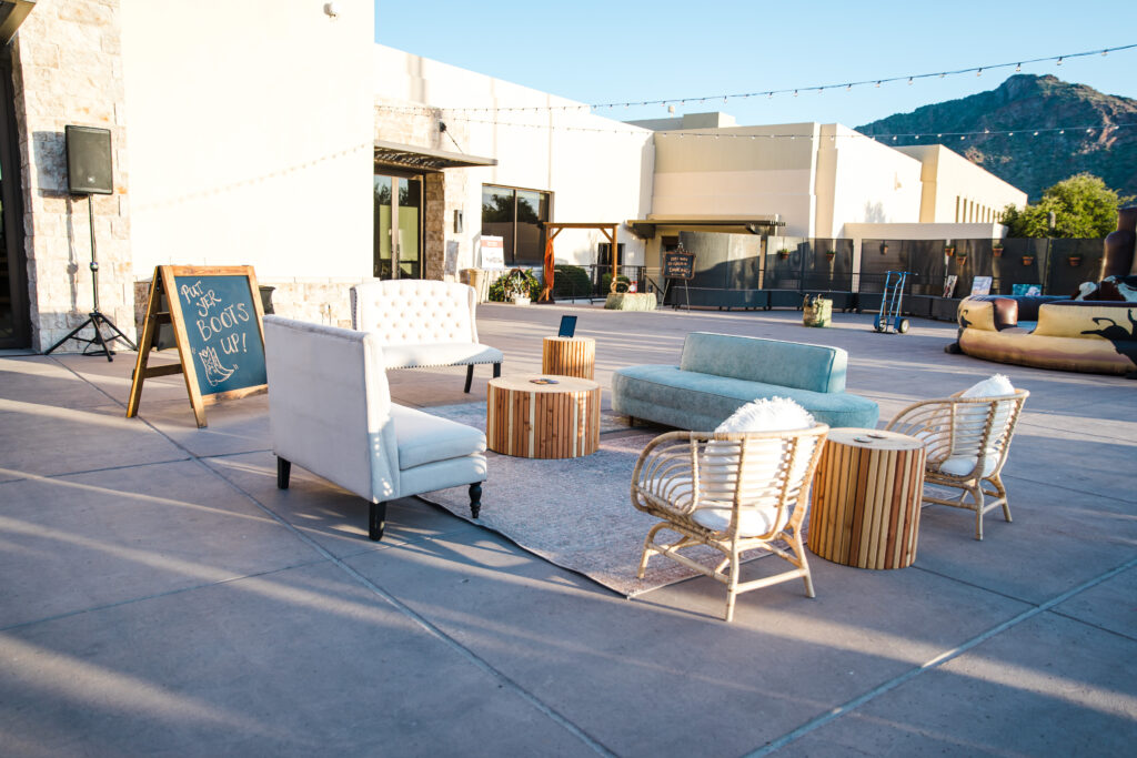 three loveseats and two wicker chairs around a rug and round coffee table at an outdoor event