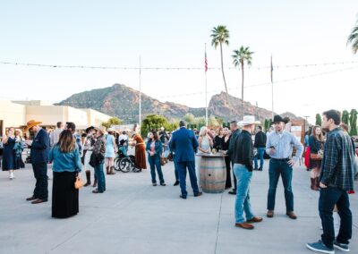 Guests standing under string lighting at an outdoor wedding