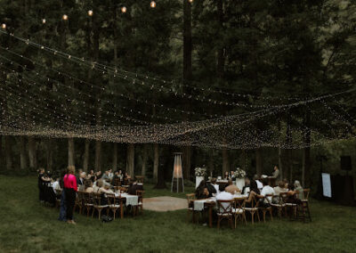 Small outdoor reception with twinkle lighting over tables and a dance floor