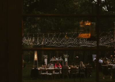 Small outdoor reception with twinkle lighting over tables and a dance floor