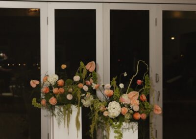 Floral pieces set atop two white columns at an indoor wedding