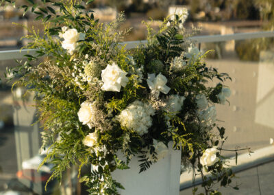 White plant stand topped with large floral arrangement at an outdoor arizona wedding