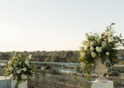 Two white plant stands topped with large floral arrangements at an outdoor arizona wedding